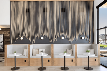 A restaurant with white tables and benches and a large feature wall with white lamps